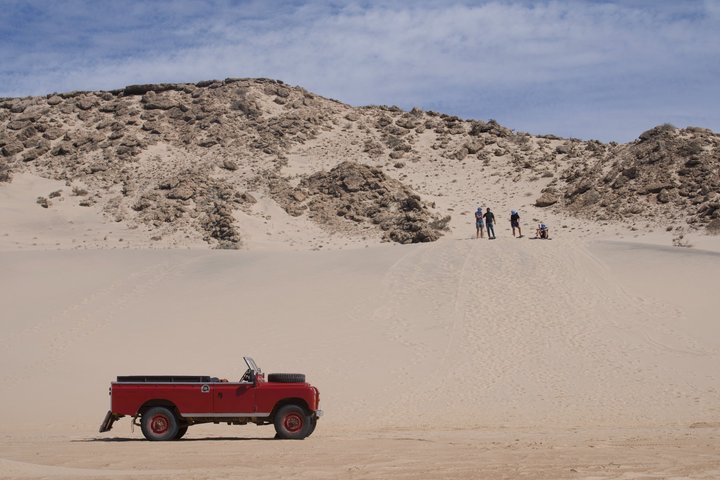 Exploración y sandboarding en las dunas blancas con un Land Rover Safari clásico.