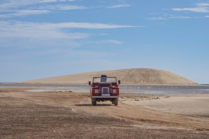Exploración y sandboarding en las dunas blancas con un Land Rover Safari clásico.