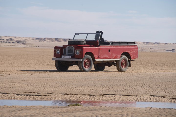 Exploración y sandboarding en las dunas blancas con un Land Rover Safari clásico.