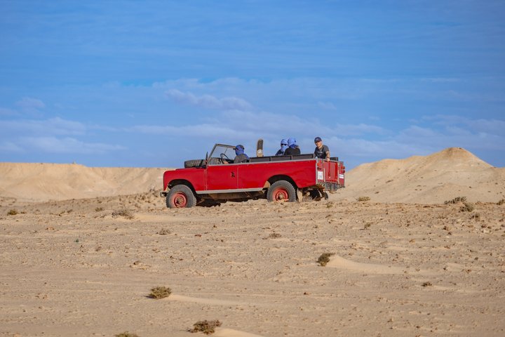 Exploración y sandboarding en las dunas blancas con un Land Rover Safari clásico.